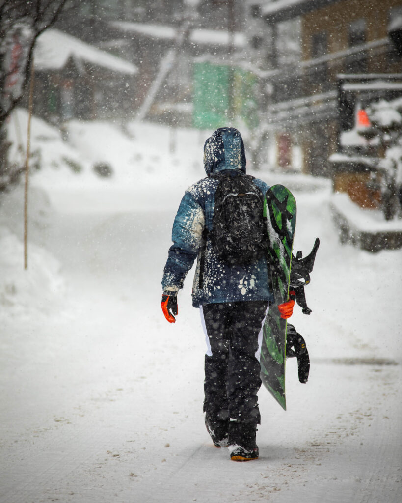 Skiing Japan - Snowboard walking down snowy road